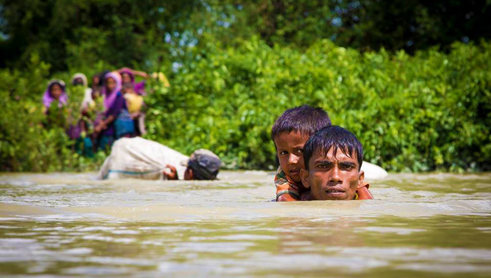 A Rohingya man carries his son on the shoulder while crossing the Naf River by swimming to enter into Anjumanpara border point of Ukhiya, Cox’s Bazar. October 13, 2017 Photo: Tushar Tohin/BenarNews 