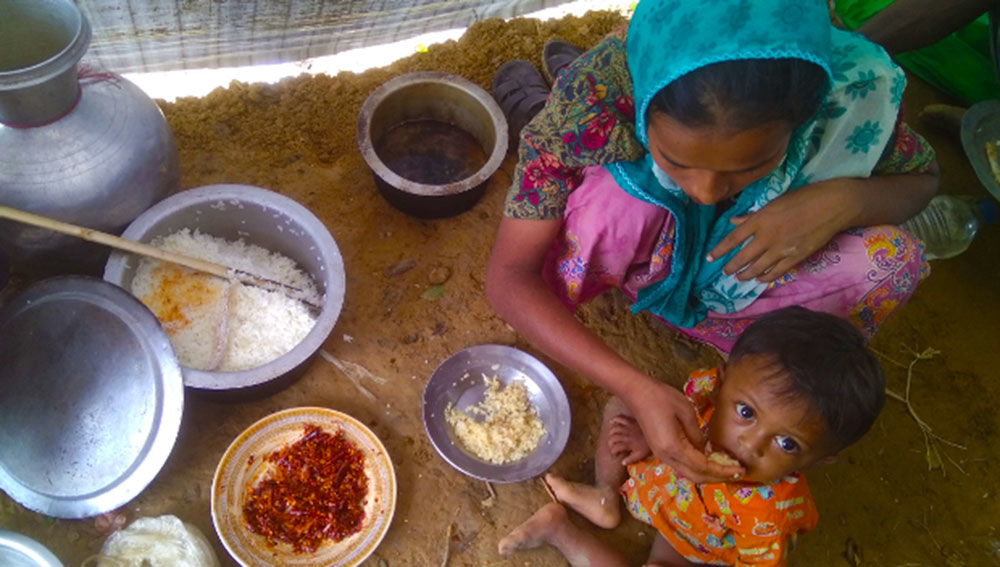 A Rohingya woman feeds her child with rice received through a distribution of relief supplies at the Kutupalong camp in Ukhia, Sept. 13, 2017. Photo: Jesmin Papri/BenarNews 