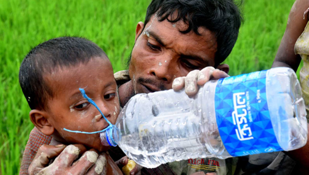 A Rohingya refugee gives water to his son as they make their way across the Myanmar border into Teknaf, Bangladesh, Sept. 6, 2017. Photo: Abdur Rahman/BenarNews 