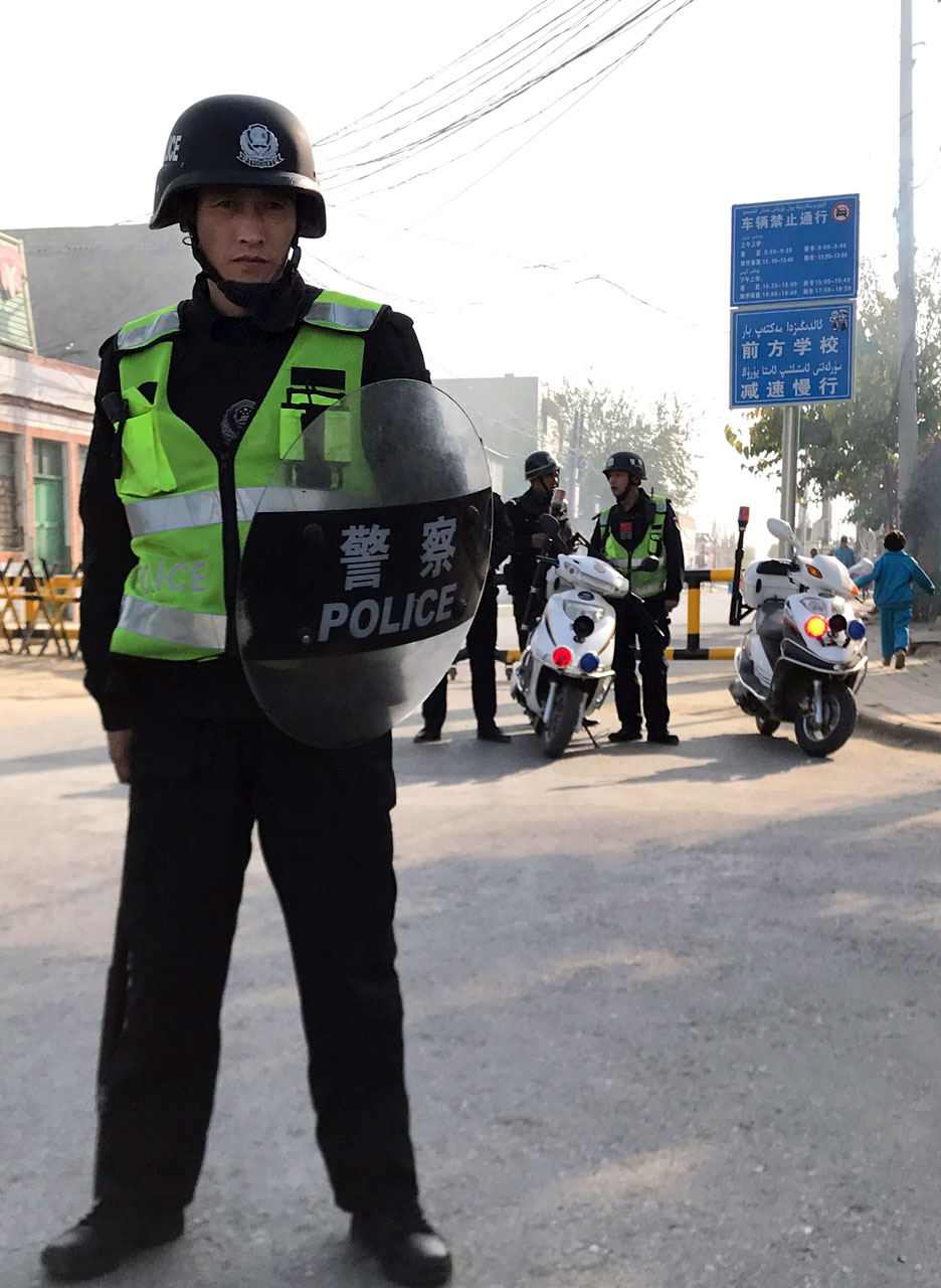 A security officer holding a shield and baton guards a security post leading into a center believed to be used for re-education in Korla, Nov. 2, 2017. Photo: AP