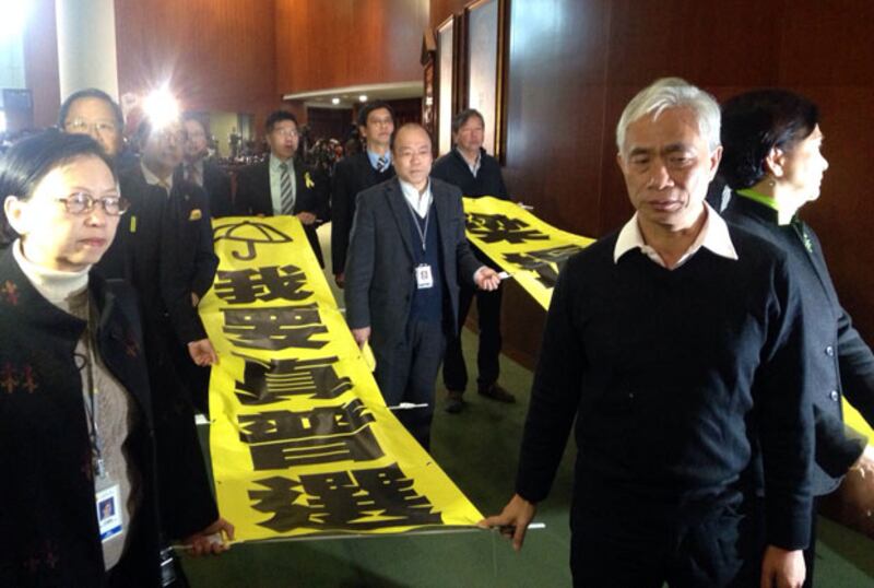 1月14日,特首梁振英進入立法會後,泛民議員手持“我要真普選”和“梁振英下台”的標語抗議。(泛民議員提供)