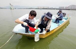 지난 여름 `호반의 도시' 춘천 의암호 일대에 최근 녹조가 발생해 비상이 걸린 가운데 공무원과 주민들이 농도 측정을 위해 시료를 채취하고 있다.