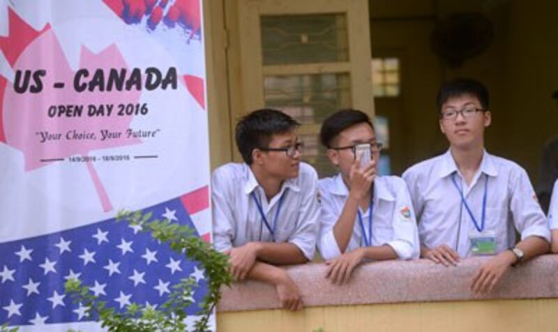 Học sinh một trường trung học ở Hà Nội đứng cạnh một tấm áp phích quảng cáo du học Mỹ - Canada ngày 4 tháng 10 năm 2016.
