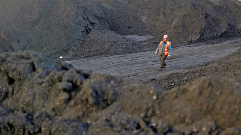 A worker walks past coal piles at a coal coking plant in Yuncheng, northern China's Shanxi province, Jan. 31, 2018.