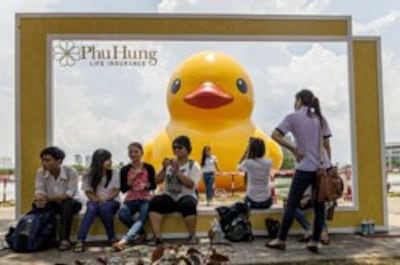 Các bạn trẻ chụp hình gần một con vịt cao su khổng lồ tại Phú Mỹ Hưng, TPHCM hôm 28 tháng 4 năm 2014. AFP photo