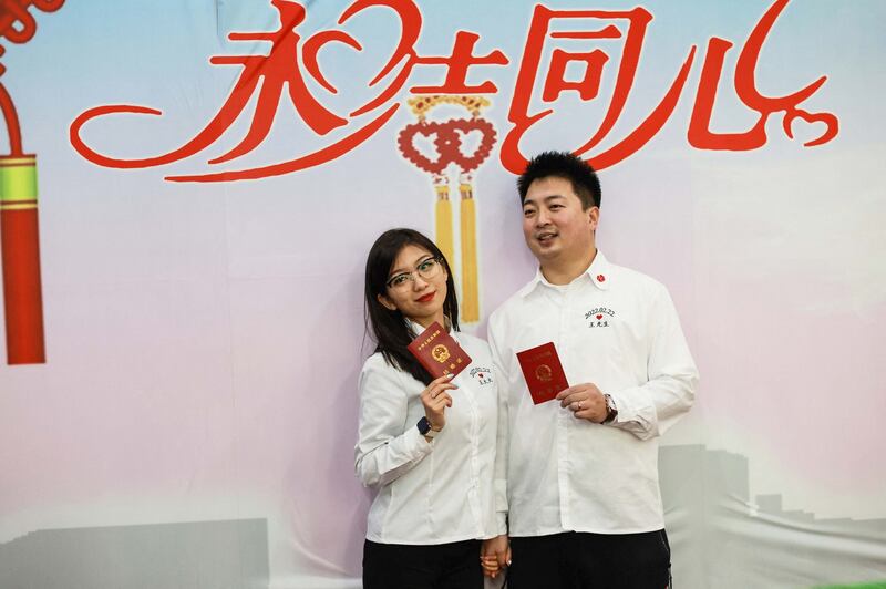 2022年2月22日,一对年轻夫妇手持结婚证在辽宁省沈阳市的婚姻登记处摆拍。将于今年6月1日起施行的《福建省妇女权益保障条例》规定,该省妇女持身份证、户口本和结婚证等证明夫妻关系的有效证件,可以依法向房地产行政管理、车辆管理等单位申请查询配偶的财产状况。 (法新社图片)