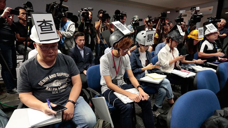 2019年11月4日，多位香港记者在头戴“查警暴止警谎”标语的头盔等候警方举行记者会。（美联社）