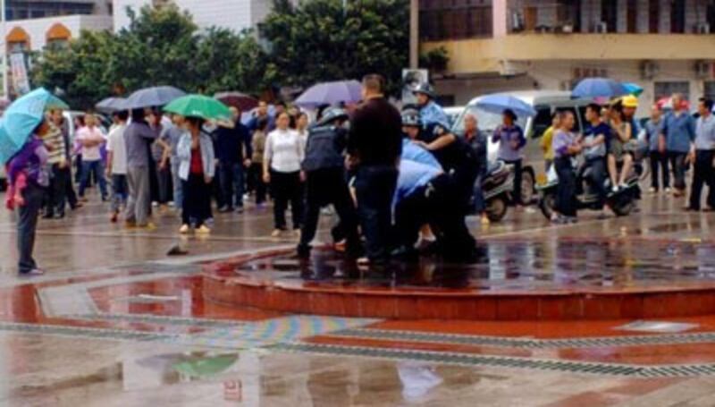 2014年4月23日，廣西省玉林市四良村村民示威反對強建公墓，特警來到現場向示威村民進行驅趕並没收橫額，有村民不服作反抗即遭到警方抬走。（村民攝）