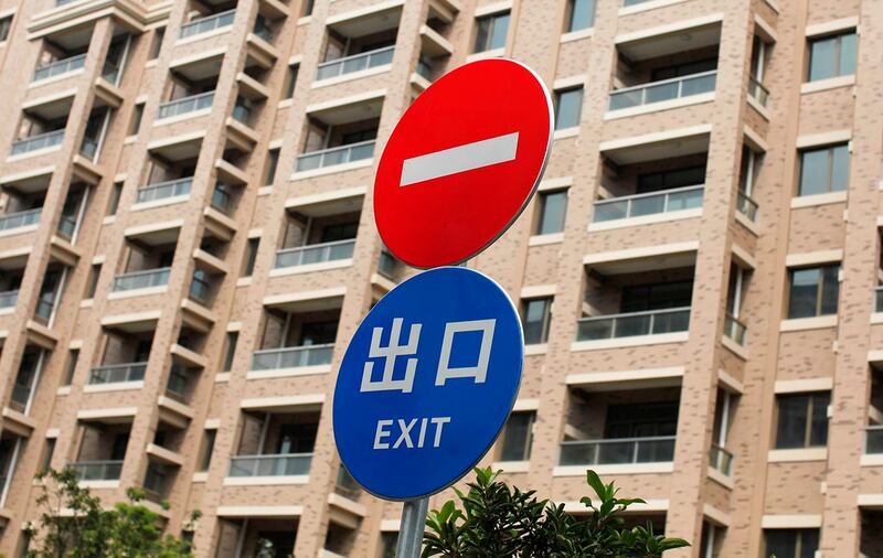图为上海市一处住宅区的道路标志,背景中是无人入住的住宅楼。(路透社)