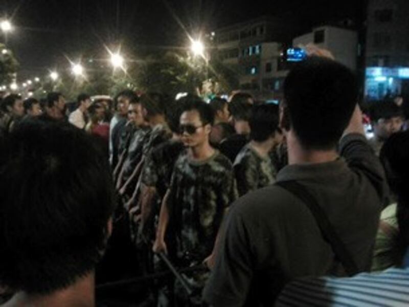 图片： 穿迷彩服的公安持棍棒保护警车。 （中国茉莉花革命网站）