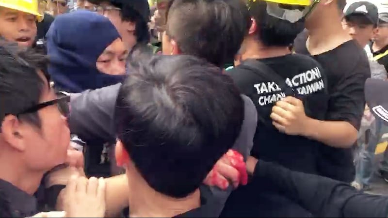 对何韵诗泼漆的人士，戴蓝色头套者，遭民众团团围住。（民众提供）
