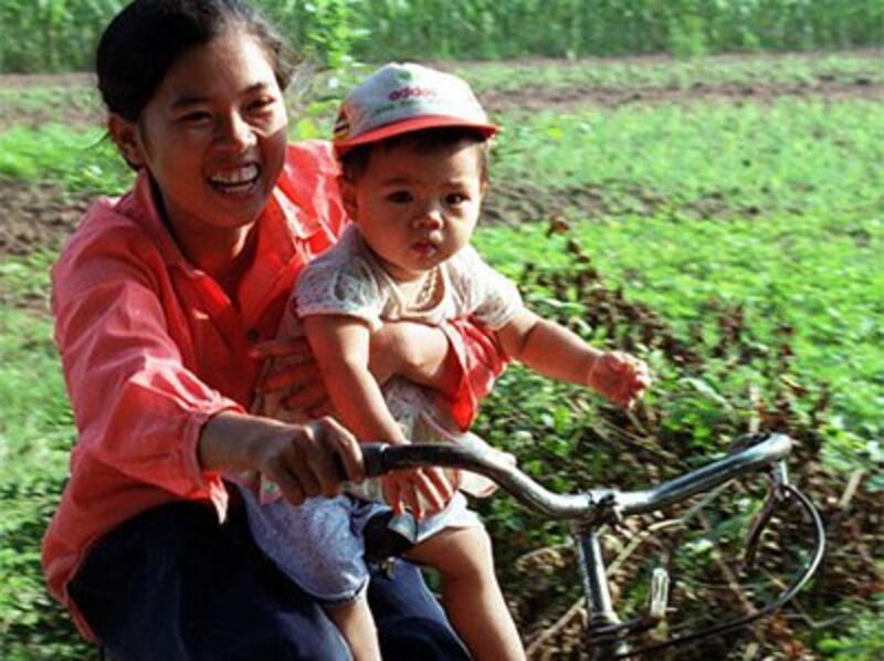 Một bà mẹ trẻ giữ con trai của cô trong khi lái xe đạp trên một con đường nông thôn tỉnh Hà Tây.