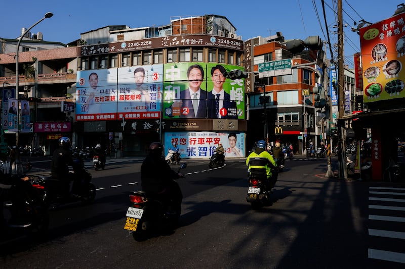 People ride past campaign ads for presidential and parliamentary candidates in ahead of the general election in Taipei, Jan. 12, 2024.
