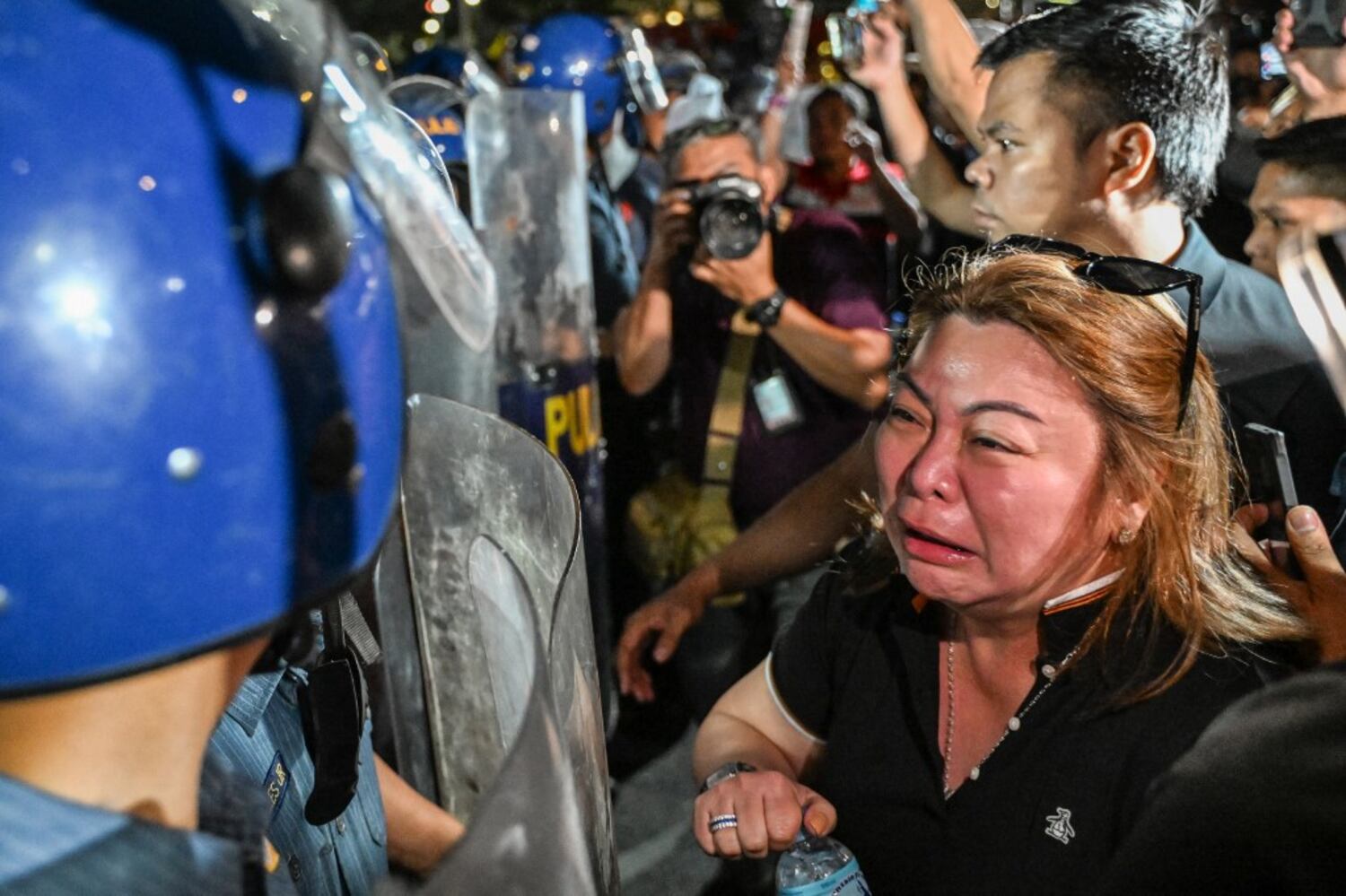 A supporter of former Philippine President Rodrigo Duterte reacts while facing police outside Villamor Air Base, where he is being held, March 11, 2025.