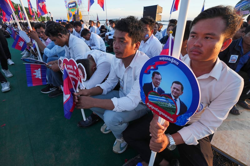Cambodian civil servants hold photographs of their Prime Minister Hun Manet and Senate President Hun Sen, during a groundbreaking ceremony of China-funded Funan Techo canal that will connect the country’s capital Phnom Penh with Kep province on the country's south coast, Prek Takeo village, Kendal province, Cambodia, Aug. 5, 2024.