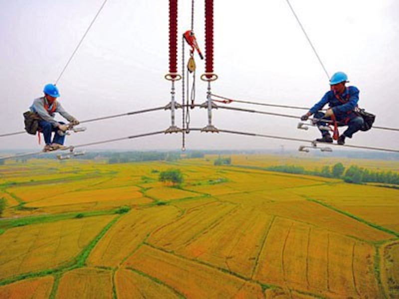 Chinese workers mount high-voltage cables over massive fields in Fengyang county of Chuzhou city in eastern China's Anhui province, May 22, 2014.