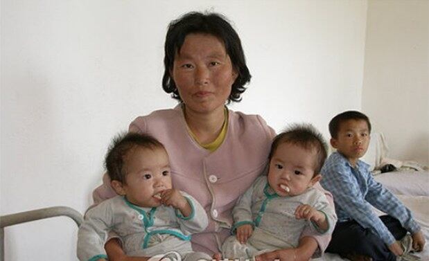 북한 함경북도 혜령시의 한 어머니가 병원에서 영양실조에 걸린 쌍둥이 어린이를 껴안고 있다.
