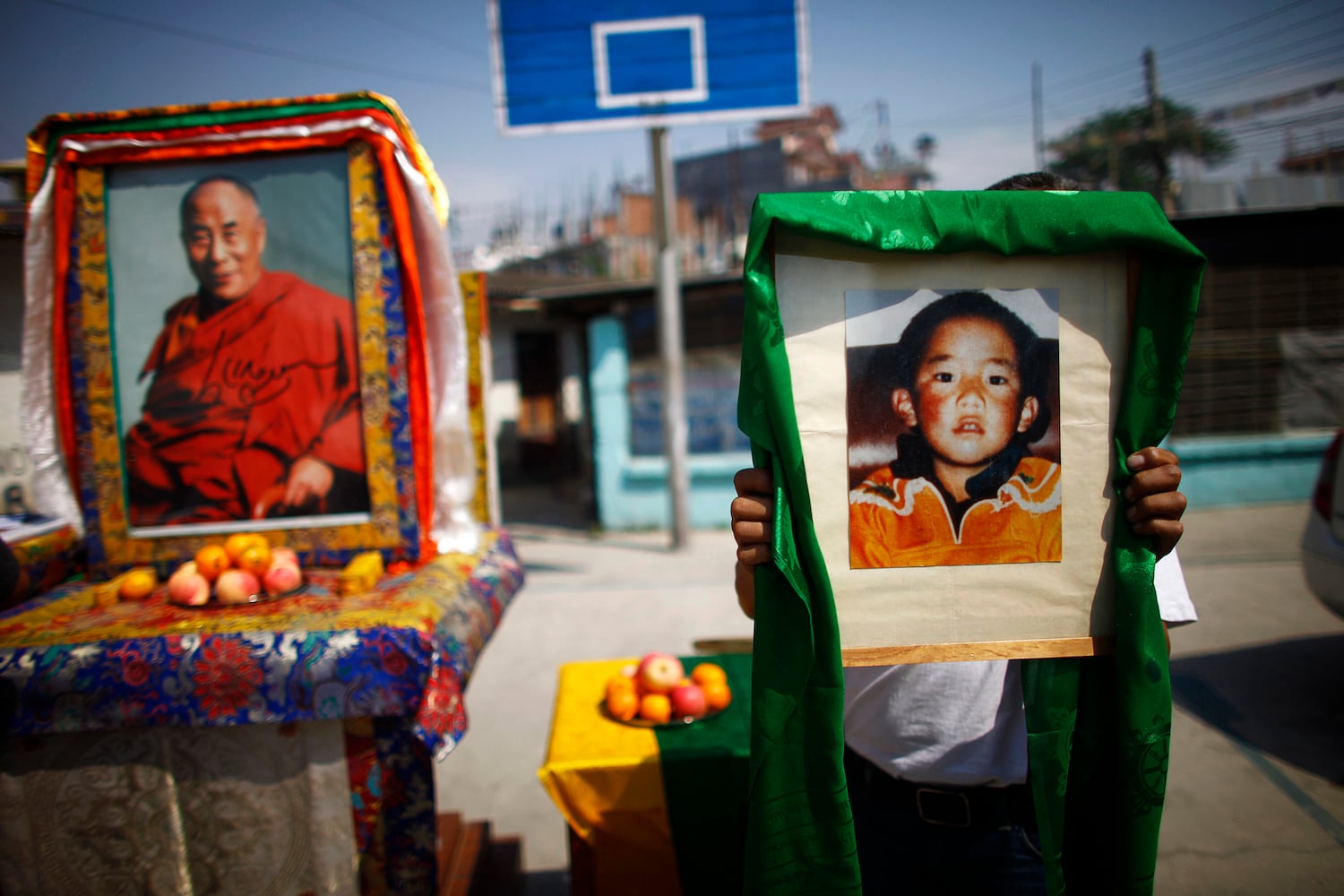 A Tibetan man carries a portrait of the 11th Panchen Lama, the second-highest Tibetan religious leader, as a portrait of the Dalai Lama, left, stands in the background, in Katmandu, Nepal, Wednesday, April 25, 2012.