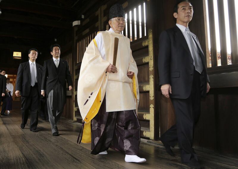 2013 年 12 月 26 日，日本首相安倍晋三（左二）跟随神道教牧师在东京靖国神社悼念战争死难者。这是自 2006 年小泉纯一郎前往纪念二战结束以来，在任首相的首次访问。（美联社）