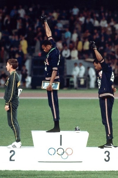 1968年墨西哥城夏季運動會上,200米賽跑冠軍史密斯(Tommie Smith)和銅牌得主卡洛斯(John Carlos)在頒獎儀式上舉起戴有黑手套的手,象徵對「黑人權利的致敬」。 (意大利米蘭非盈利組織Gariwo網站截圖)