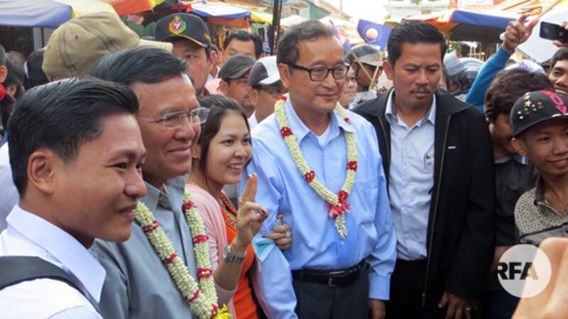 លោក សម រង្ស៊ី និង​លោក កឹម សុខា ថតរូប​ជាមួយ​ប្រជាពលរដ្ឋ និង​អាជីវករ​ផ្សារលើ ​ខេត្ត​សៀមរាប កាល​ពី​អំឡុង​​ឆ្នាំ​២០១៤។ 
