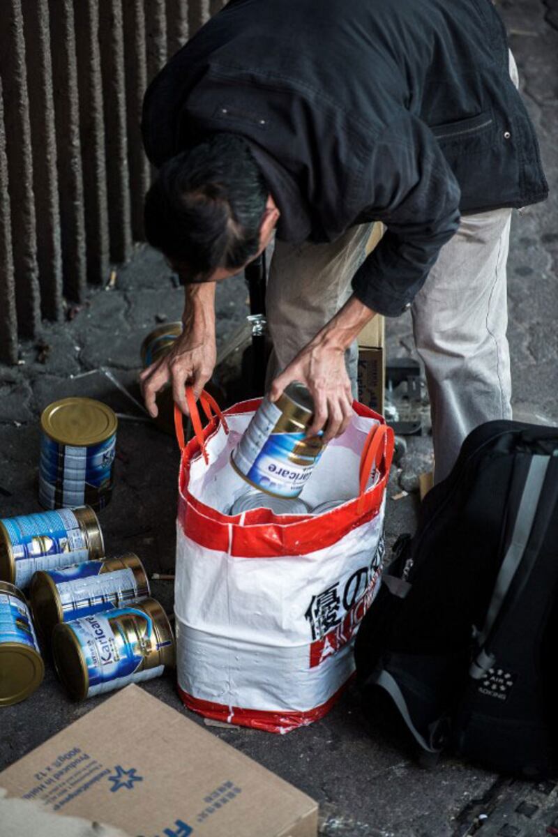 2013年1月29日，一位大陸遊客在香港上水車站整理攜帶大批嬰兒奶粉的行李。（AFP PHOTO/Philippe Lopez） 