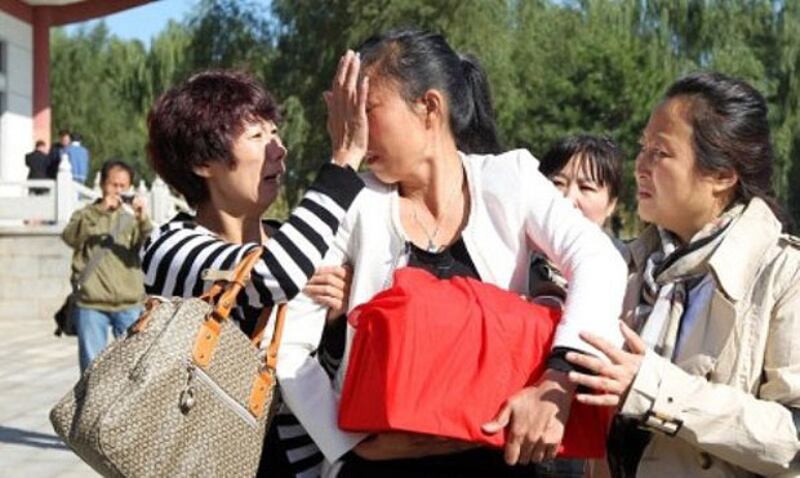 夏俊峰妻子張晶(中)手抱丈夫的骨灰,傷心落淚。(照片由微博下載,經張晶同意使用)