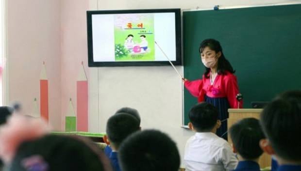 여성들이 북한에서 제일 많이 종사하는 분야가 교육 분야이다. 사진은 평양시 대성구역 려명소학교에서 여교사가 분홍색 마스크를 쓴 채로 교실 앞 스크린을 가리키며 수업하고 있다.