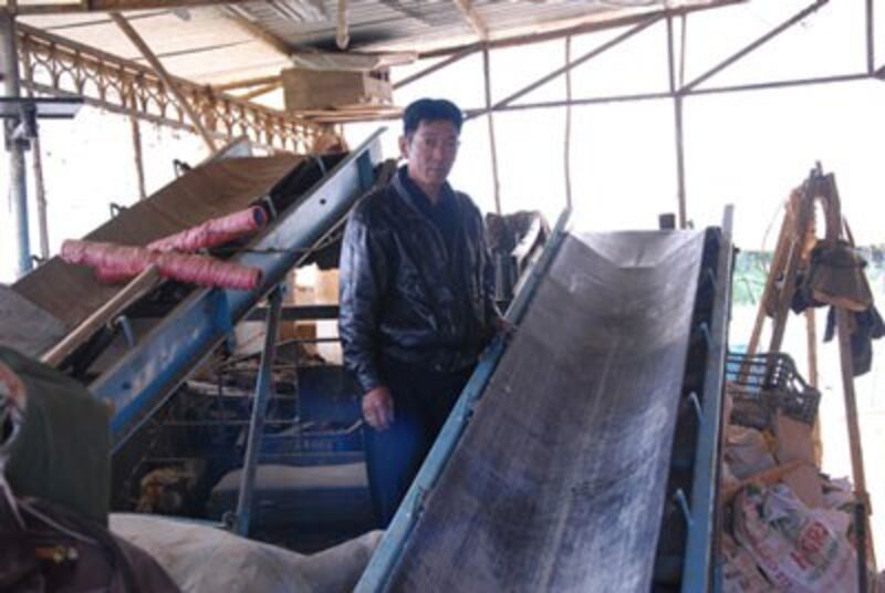Ông Vũ Đình Phúc và một phần chiếc máy xử lý phế phẩm nông nghiệp thành phân hữu cơ vi sinh. Photo courtesy of tintaynguyen.