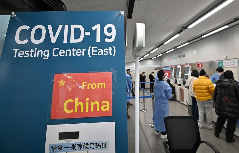 2023 年 1 月 3 日,卫生工作者在首尔仁川国际机场的 Covid-19 检测中心指导来自中国的旅客。(法新社)