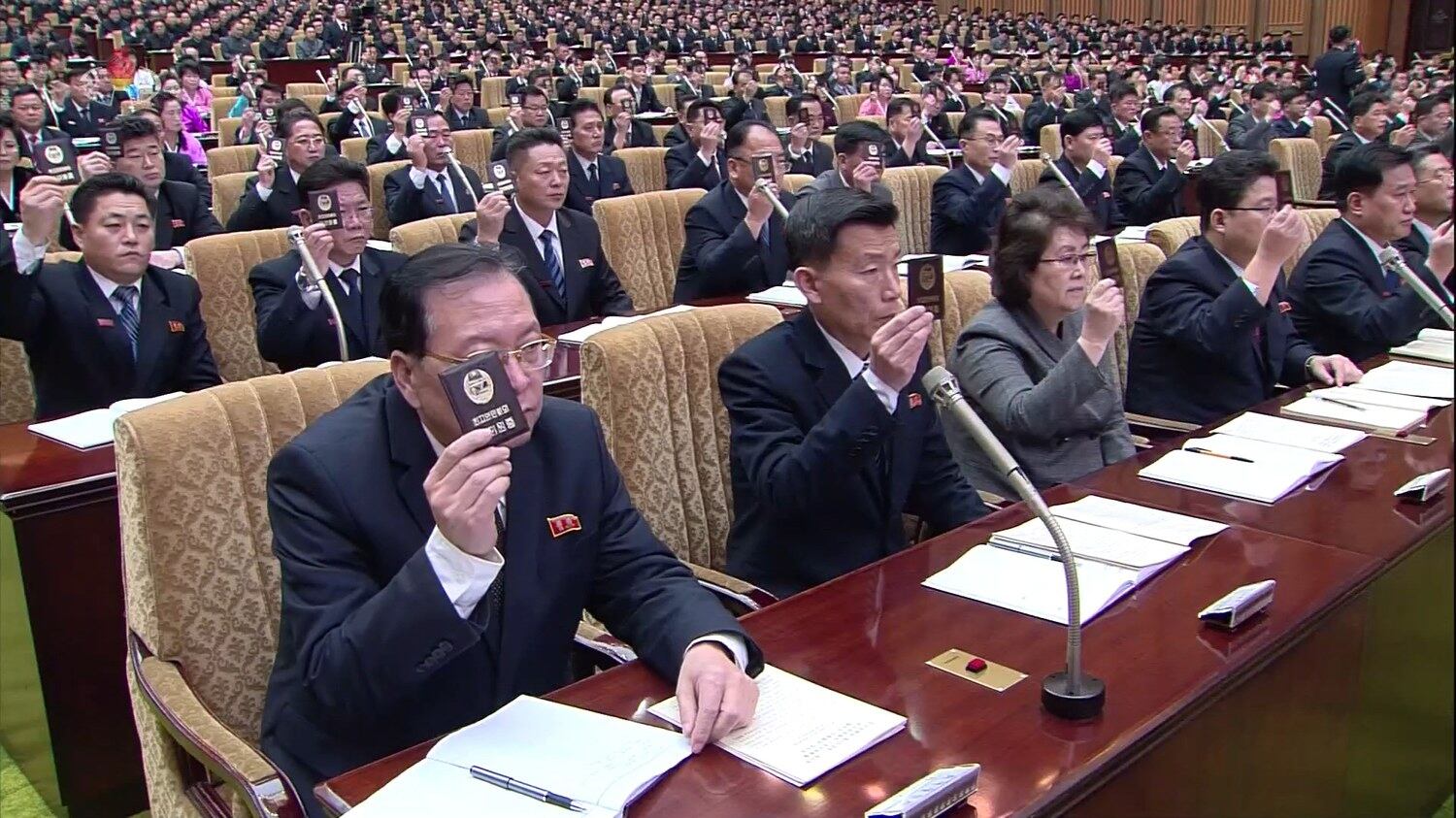 사진은 최고인민회의에 참석한 대의원들이 자리에 착석한 채 대의원증을 들어 올리는 모습.