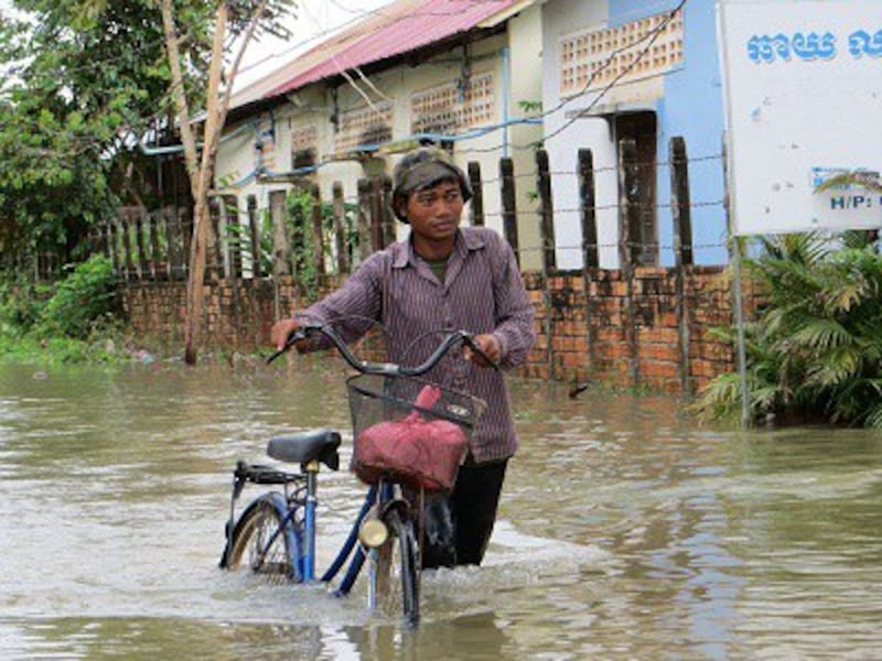 A man walks his bike along a flooded street in Cambodia's Siem Reap, Oct. 1, 2013. Photo credit: RFA.