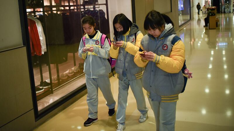 三年前在中国进行的调查显示，接近七成中国中小学生拥有智能手机，比例超过美国和日本学生。图为，2018年1月26日，学生们在北京一家购物中心使用手机。 （法新社图片）