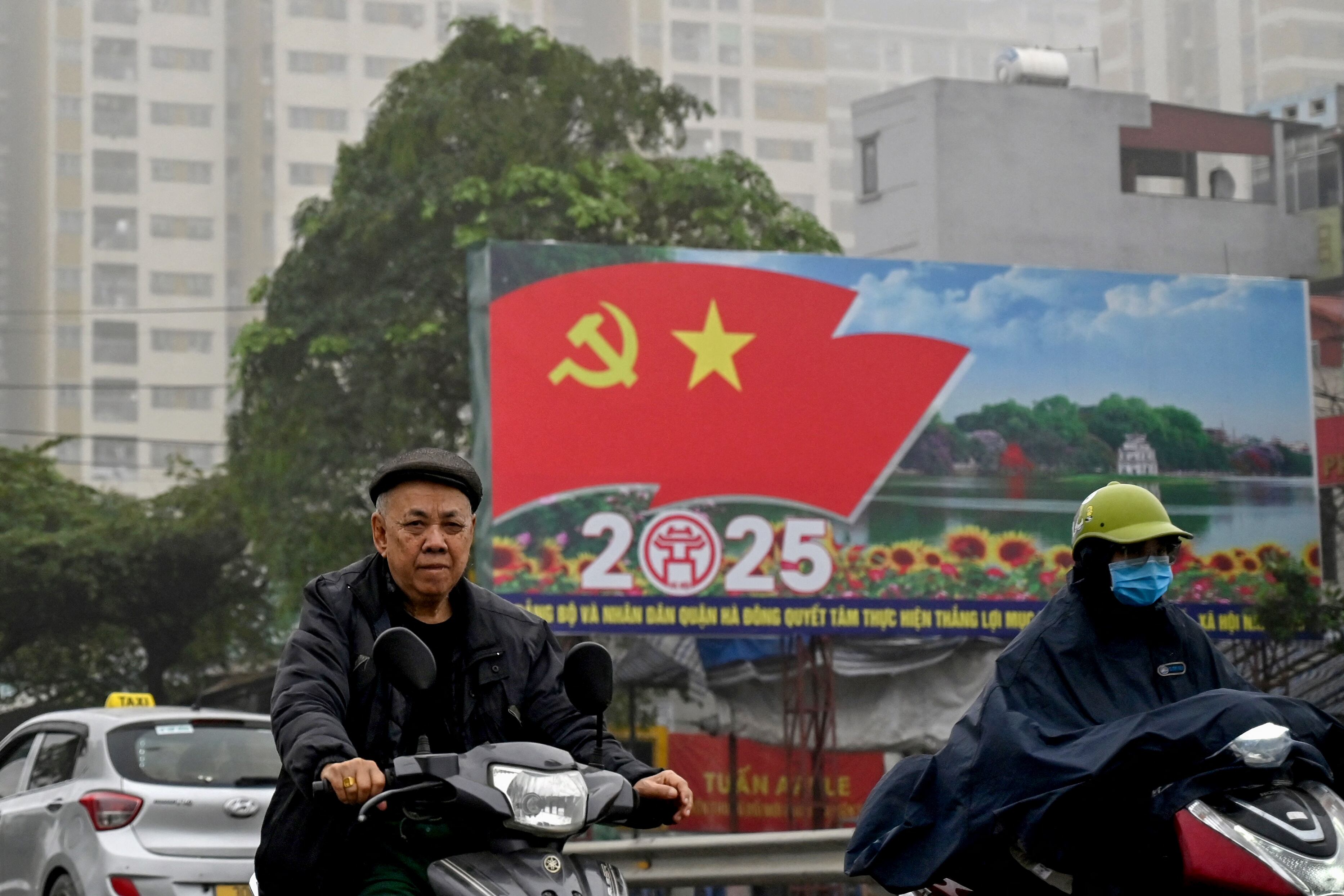 Commuters ride scooters amid heavy air pollution in Hanoi on March 5, 2025. (Photo by Nhac NGUYEN / AFP)