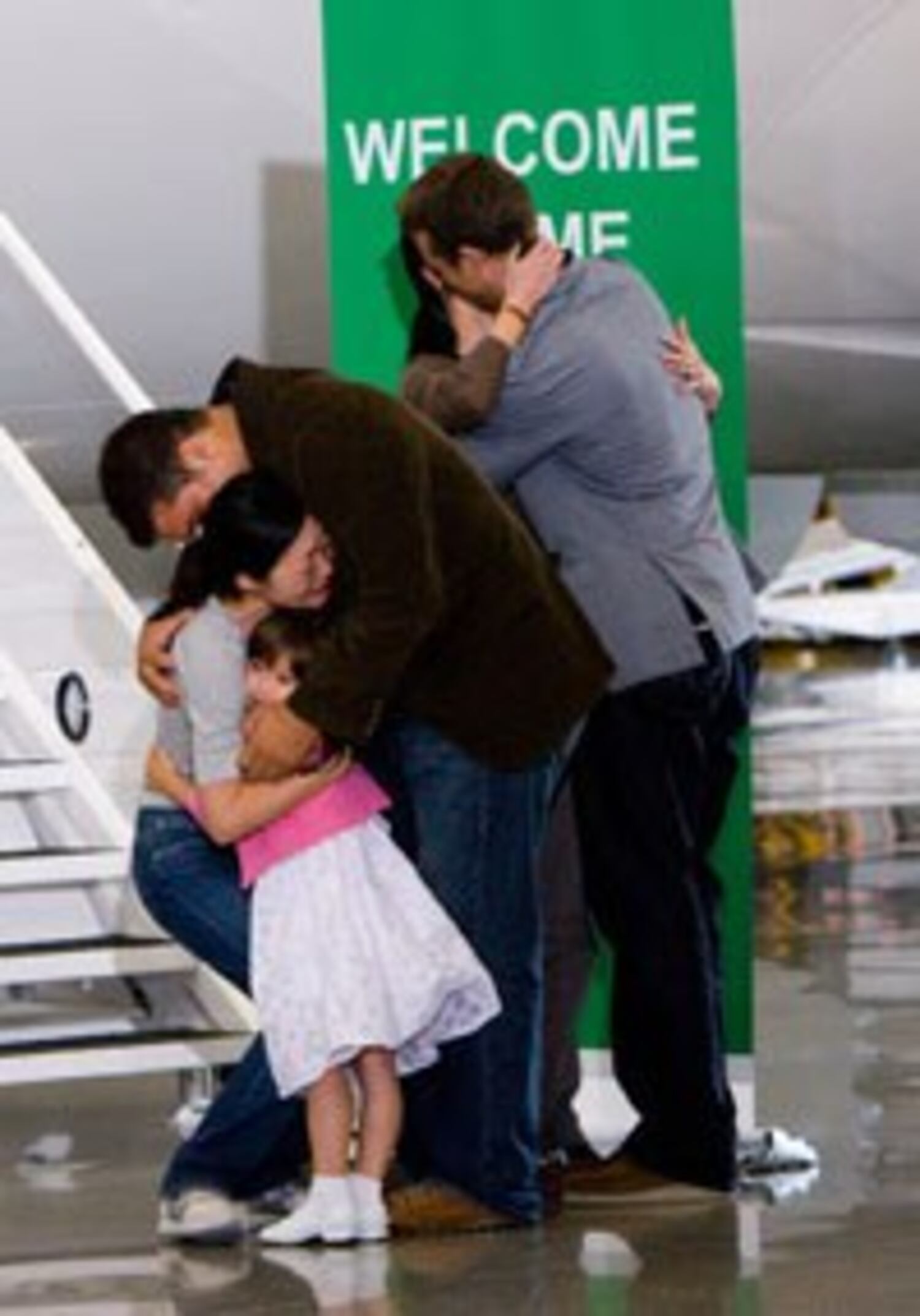 Ms. Lee, in tears, embraces her husband, Michael Saldate, and kneels to hug her 4-year-old daughter, Hana. Ms. Ling kisses her husband, Iain Clayton upon their return from North Korea at Bob Hope Airport in Burbank, on Aug. 5, 2009. Photo: RFA/Xiao Rong
