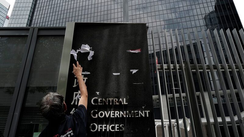 一名工人在清理香港政府大楼上的标语。(美联社)