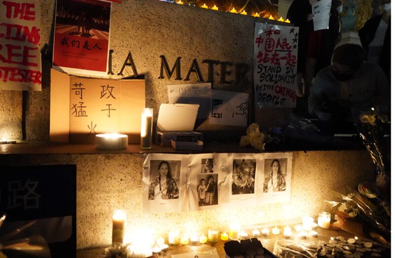 参与集会的学生将“智慧女神”雕像的底座设置成祭台,贴上乌鲁木齐11.24火灾死难者照片和海报,奉上鲜花和蜡烛。(记者艾玛摄)