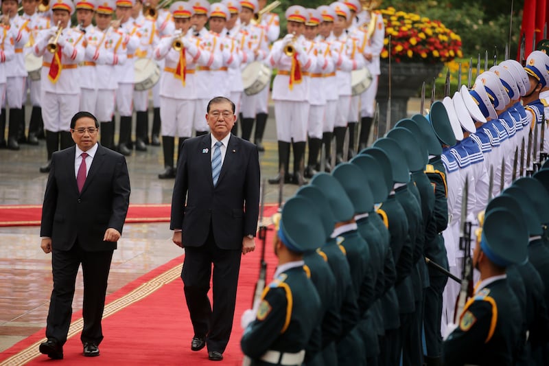 Vietnamese Prime Minister Pham Minh Chinh, left, and his Japanese counterpart Shigeru Ishiba review the guard of honor at the Presidential Palace in Hanoi, Vietnam Monday, April 28, 2025. (Luong Thai Linh/Pool Photo via AP)