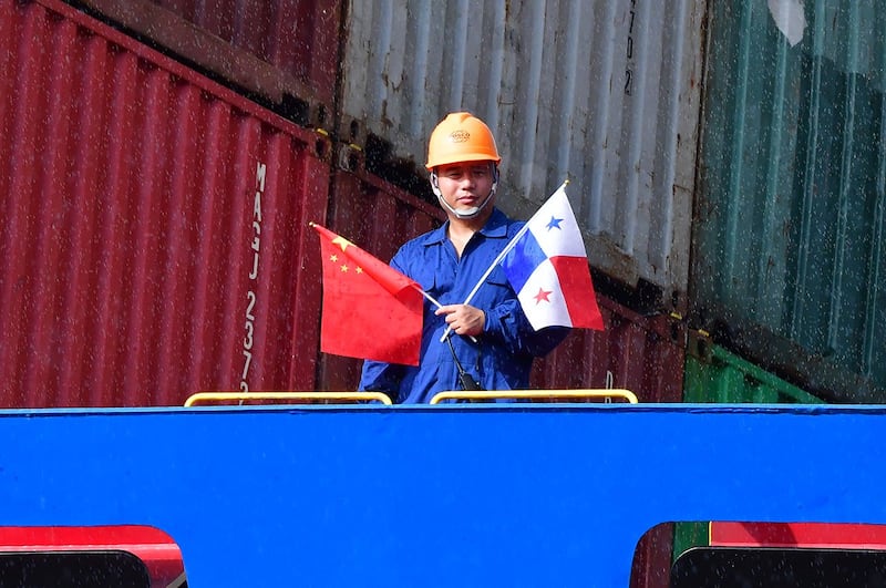 2018 年 12 月 3 日,中国中远海运玫瑰集装箱船员工手持旗帜在巴拿马运河新落成的可可利船闸旁。(法新社)