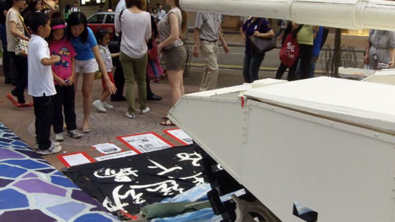 香港時代廣場外的地上擺放當年有關“六四事件”的《文匯報》複印本，圍觀的家長向小朋友講解。（粵語部王鳳萍攝）