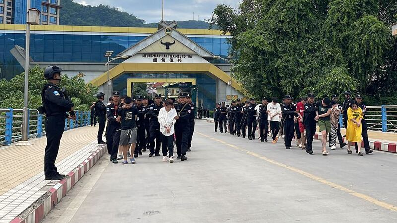 'ဝ' ကိုယ်ပိုင်အုပ်ချုပ်ခွင့်ရဒေသရှိ အွန်လိုင်းငွေလိမ်ဂိုဏ်းများတွင် ပါဝင်လုပ်ကိုင်နေသည့် တရုတ်နိုင်ငံသားများအား UWSA 'ဝ' တပ်ဖွဲ့က ၂၀၂၃ ခုနှစ်၊ စက်တင်ဘာလ ၇ ရက်နေ့တွင် နယ်စပ်မှတစ်ဆင့် တရုတ်နိုင်ငံသို့ လွှဲပြောင်းပေးနေစဉ်။ (Photo: WSTV)
