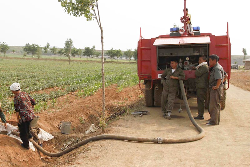 North Koreans use a truck to pump water into a field in Kohyon-ri, North Korea in the country's Hwangju County.