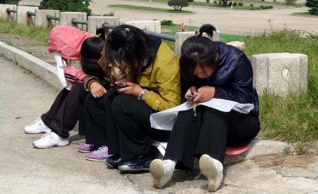 평양의 젊은 여성들이 손전화를 들여다 보며 뭔가를 하고 있다.