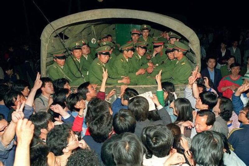 被阻止前行的军车上，军人目光木纳，而车下百姓群情激愤：你们明白真相吗？（Public Domain）