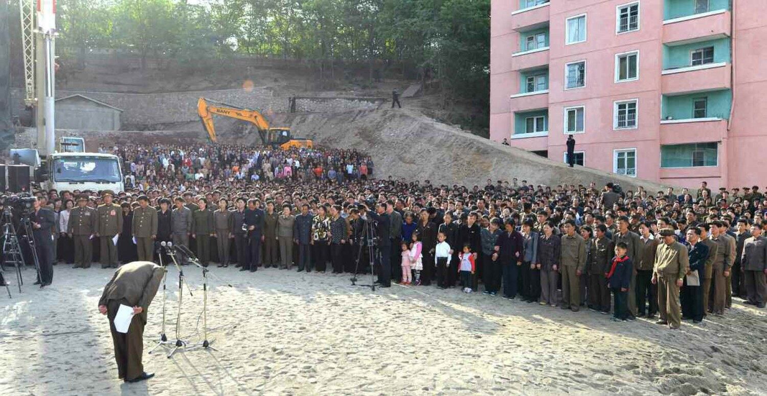 2014년 5월 13일 평양 평천구역 아파트 붕괴 사고 발생 나흘 뒤 인민보안성 고위 장성이 깨끗이 정리된 붕괴 현장에서 수백명의 유가족에게 사과하고 있다.