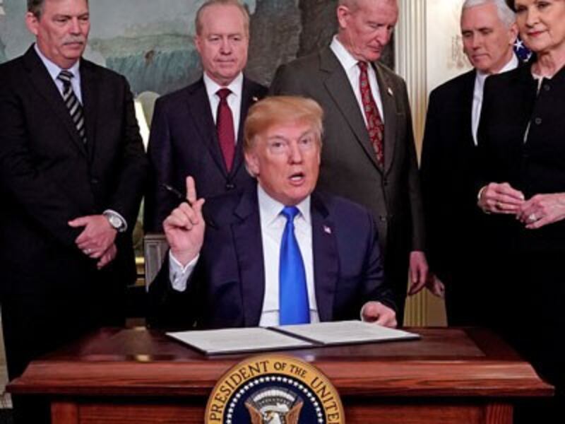 US President Donald Trump, surrounded by business leaders and administration officials, prepares to sign a memorandum on intellectual property tariffs on high-tech goods from China at the White House in Washington, March 22, 2018.