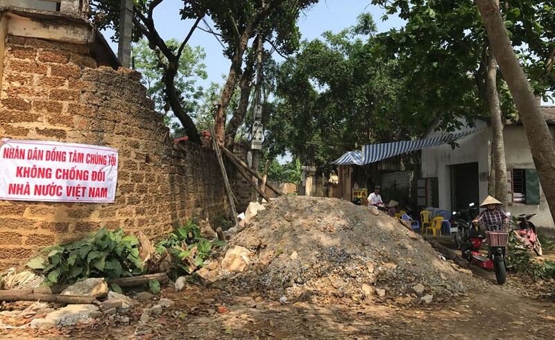 Người dân làng Đồng Tâm đi qua một đoạn đường bị chặn bởi gạch và gỗ hôm 20/4/2017