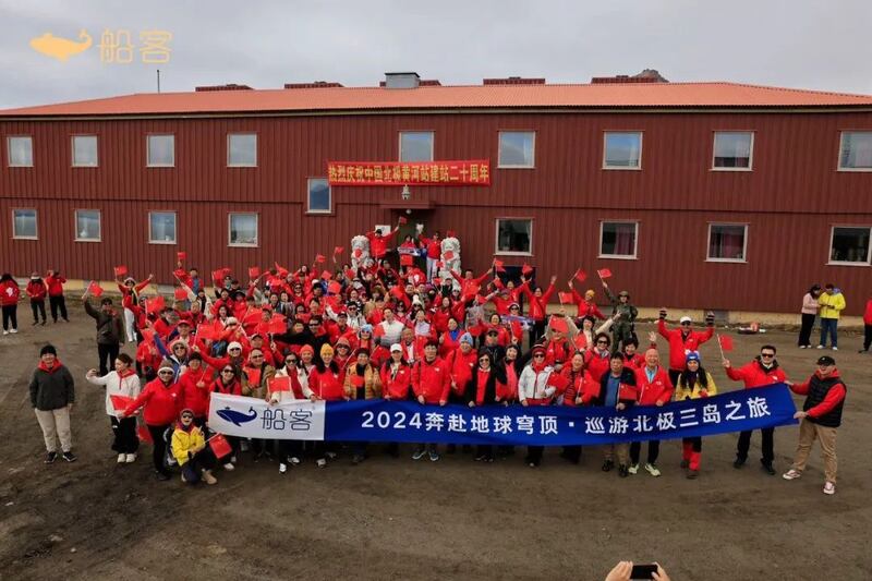 在挪威斯瓦尔巴群岛，2024年7月，中国游客在黄河站前挥舞国旗，画面右上角出现一名身穿解放军制服的女子。（图片来源:船客旅行社）