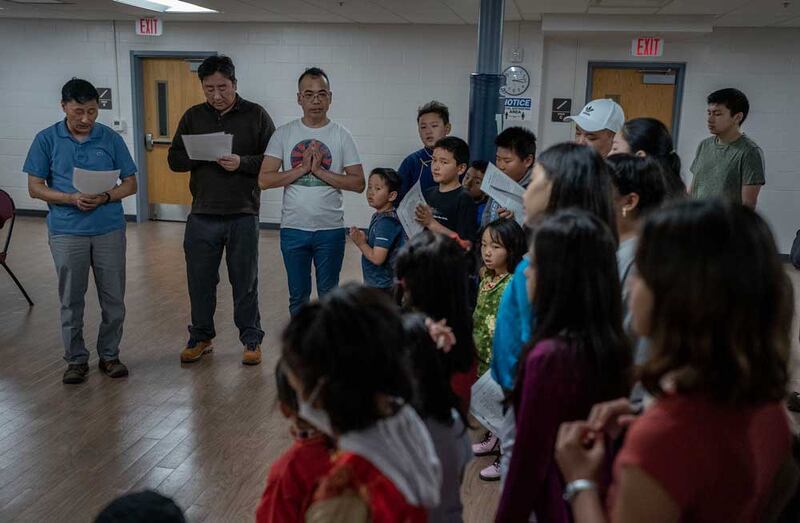 Capital Area Tibetan Association board members from left, Kalasang Dorjee [also principal of the school], Tenzing Norbu, and volunteer teacher Passang Dhonden lead the recitation of a Buddhist prayer during the opening assembly at the Tibetan language school at Vienna Community Center in northern Virginia, Sunday, May 7, 2023. Credit: Gemunu Amarasinghe/RFA