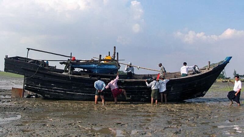 Myanmar local officials check the abandoned boat of Rohingya Muslims who washed ashore in Kyauktan township south of Yangon, Nov. 16, 2018.